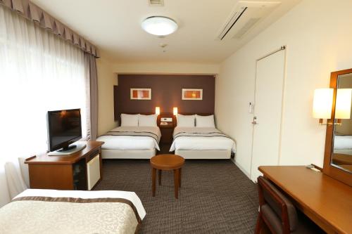 a hotel room with two beds and a television at Hotel Hokke Club Osaka in Osaka