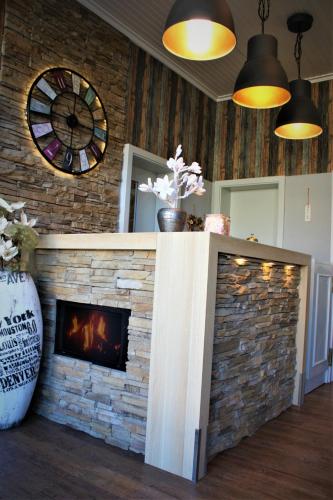 a living room with a stone fireplace with a clock at Hotel am Kurpark in Bad Lauterberg