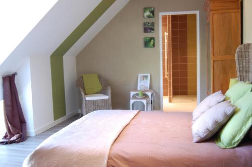a bedroom with a bed and a chair in a attic at Maison d'hôtes & Gîtes Domaine de la Garaye in Dinan