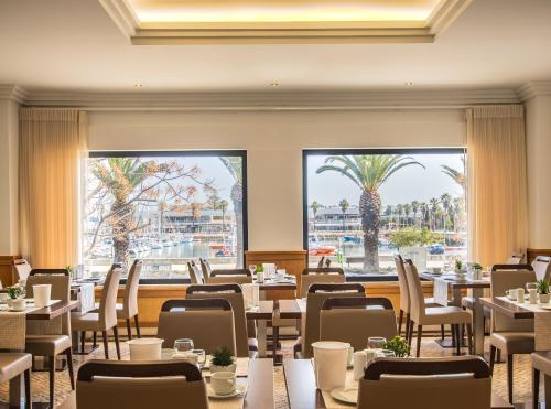 a dining room with tables and chairs and palm trees at Hotel Marina Rio in Lagos