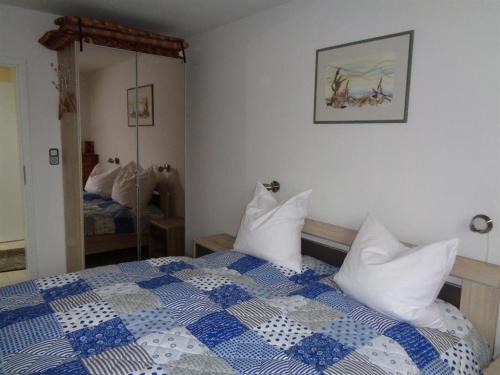 Schlafzimmer mit einem blauen und weißen Bett und einem Spiegel in der Unterkunft Ferienhaus "Pusteblume" in Bad Zwischenahn
