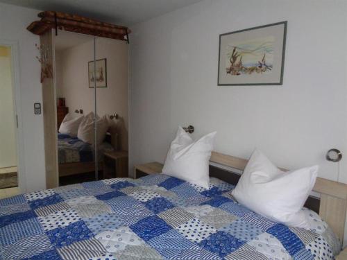 a bedroom with a blue and white bed and a mirror at Ferienhaus "Pusteblume" in Bad Zwischenahn