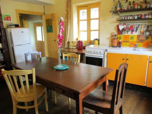 une cuisine avec une table en bois et des chaises et une cuisine avec un évier dans l'établissement Le petit Fort Fleuri, à Bellac