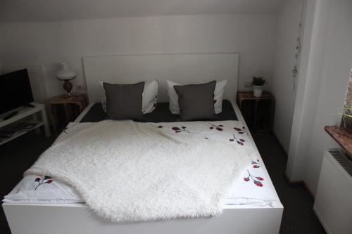 a white bed with a white blanket and pillows at Apartmentshaus Elbblick Zimmer "Bergblick" in Bad Schandau