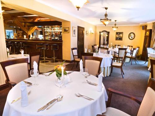 a restaurant with white tables and chairs and a bar at Hotel Lubicz in Ustka