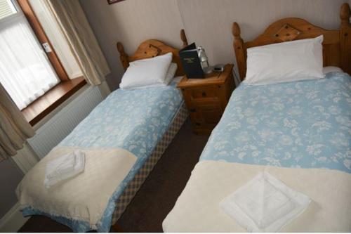 1 dormitorio con 2 camas y 1 mesa con ventana en Queens hotel, en Wick