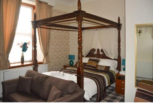 a bedroom with a canopy bed and a couch at Queens hotel in Wick