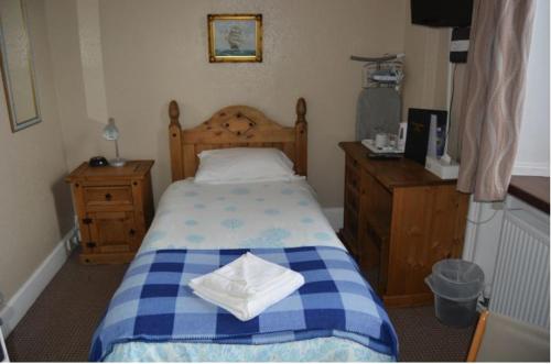 Schlafzimmer mit einem blauen und weißen Bett und Holzmöbeln in der Unterkunft Queens hotel in Wick