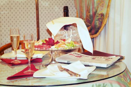 a table with a plate of food and two glasses of wine at Hotel Motel Visconteo in Binasco