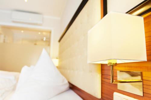 a bed with a white pillow and a lamp at Naturhotel Rügers Forstgut in Mespelbrunn