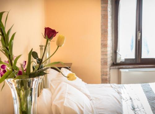 a vase of flowers sitting on a table next to a bed at Agriturismo Il Giardino Dei Ciliegi in Passaggio Di Assisi