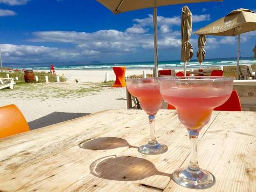 two martini glasses sitting on a wooden table at the beach at Dawn's Place in Hermanus