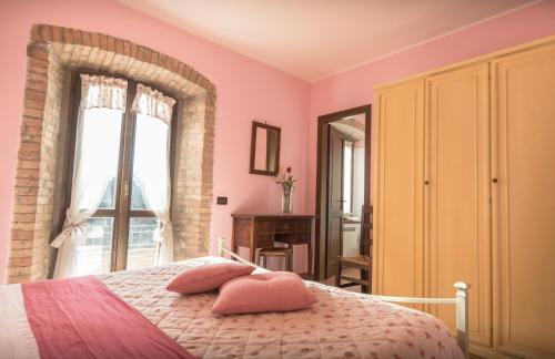 a bedroom with pink walls and a bed with pink pillows at Agriturismo Il Giardino Dei Ciliegi in Passaggio Di Assisi