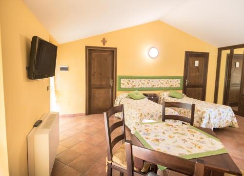 a room with two beds and a table and a tv at Agriturismo Il Giardino Dei Ciliegi in Passaggio Di Assisi