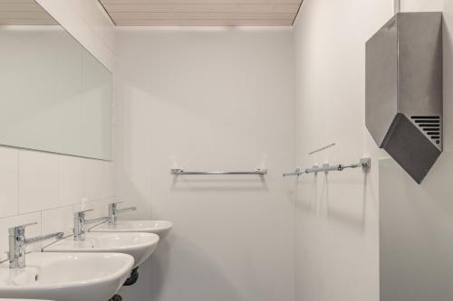 a bathroom with two sinks and a mirror at Mountain Lodge Backpackercamp in Lenk