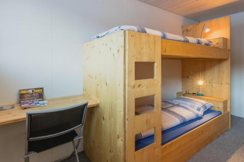 a bunk bed with a desk and a chair in a room at Mountain Lodge Backpackercamp in Lenk