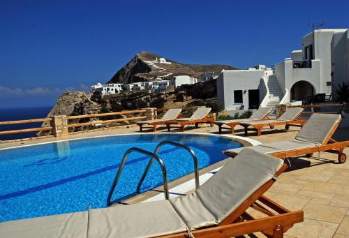 a swimming pool with chairs and a view of the ocean at Anemousa Hotel in Chora Folegandros