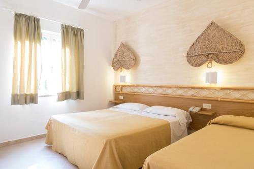 a hotel room with two beds and a window at Hotel Villaggio Cala Di Volpe in Capo Vaticano