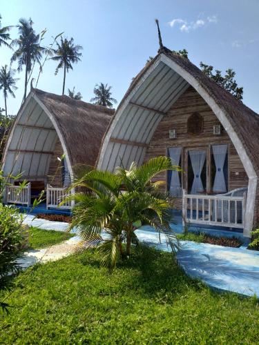 a house with a thatched roof and a palm tree at Casa Azzurra in Gili Islands