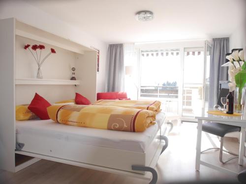 a white bedroom with a bed with yellow and red pillows at Appartement Allgäu-Sonne in Scheidegg