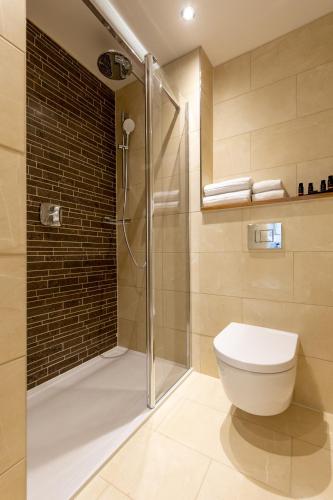 a bathroom with a toilet and a glass shower at Sandhills Apartments, Mudeford in Christchurch
