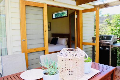 eine abgeschirmte Veranda mit einem Tisch und einem Bett in der Unterkunft Nagoondie Studio in Healesville