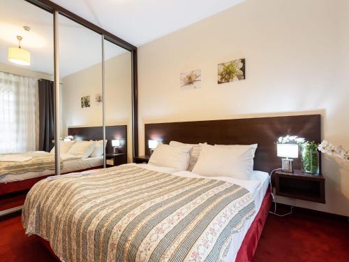 コウォブジェクにあるVacationClub - Olympic Park Apartment B5のベッドと大きな鏡が備わるホテルルームです。