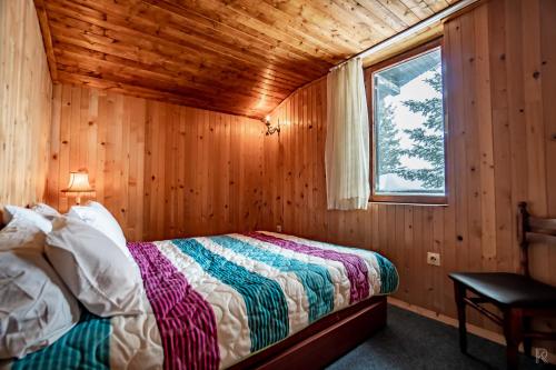 ein Schlafzimmer mit einem Bett in einer Holzhütte in der Unterkunft Villa 99 in Popova Shapka