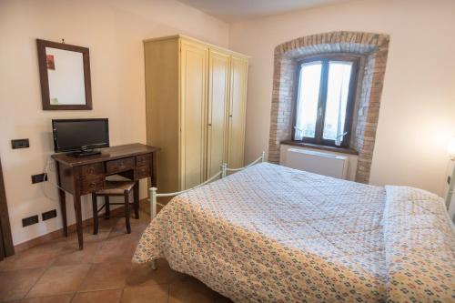 a bedroom with a bed and a desk and a television at Agriturismo Il Giardino Dei Ciliegi in Passaggio Di Assisi