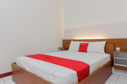 um quarto com uma cama com um cobertor vermelho em KoolKost Syariah near Ayani Mega Mall Pontianak em Pontianak