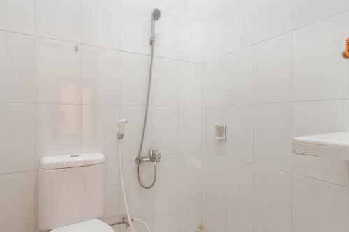 uma casa de banho branca com um chuveiro e um WC. em KoolKost Syariah near Ayani Mega Mall Pontianak em Pontianak