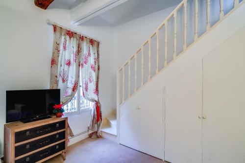 a living room with a staircase and a tv at Villa Escudier Appart-hôtel in Boulogne-Billancourt