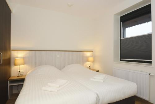ein weißes Bett in einem Zimmer mit Fenster in der Unterkunft Hotel Graaf Bernstorff in Schiermonnikoog