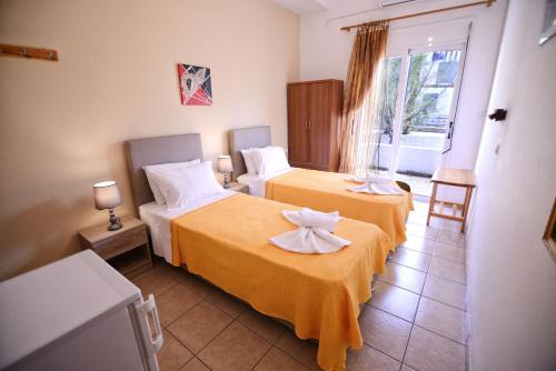 a hotel room with two beds and a window at To Gefyraki Rooms in Agios Kirykos