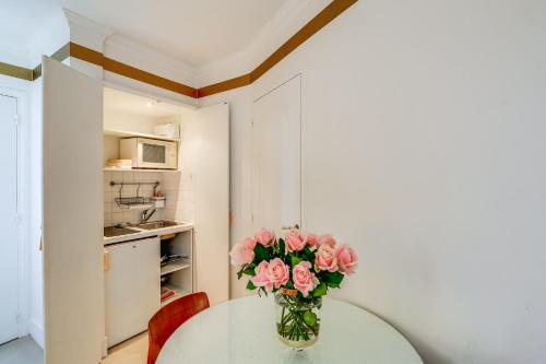 a vase of pink roses sitting on a table in a room at Villa Escudier Appart-hôtel in Boulogne-Billancourt