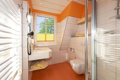 a bathroom with a toilet and a sink and a window at Dünenhotel am Meer in Warnemünde