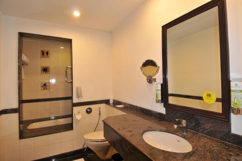 a bathroom with a sink and a toilet and a mirror at Lemon Tree Hotel, East Delhi Mall, Kaushambi in Ghaziabad