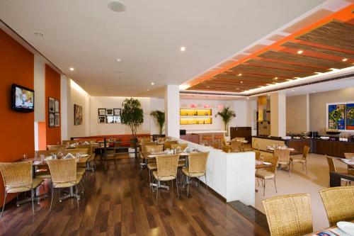 a dining room with tables and chairs in a restaurant at Lemon Tree Hotel, East Delhi Mall, Kaushambi in Ghaziabad