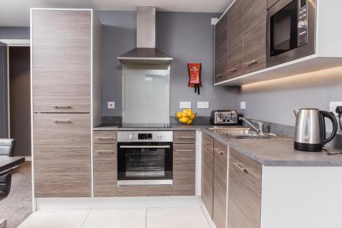 a kitchen with stainless steel appliances and wood cabinets at Dream Apartments St Thomas Hall in Belfast