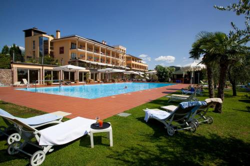 a swimming pool with lounge chairs and a resort at Boffenigo Panorama & Experience Hotel in Costermano