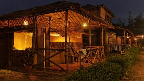 a small house with a thatched roof at night at Beach Street Eco Resort - Mandrem in Mandrem