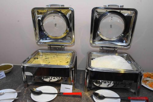 three trays of food sitting on a table with spoons at HOTEL KEK GRAND PARK in Chennai