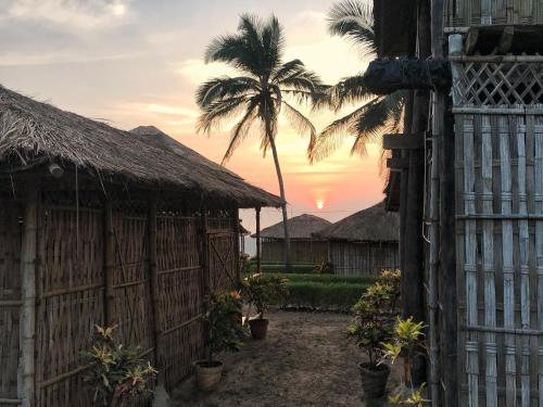 a house with a fence and a palm tree at Beach Street Eco Resort - Mandrem in Mandrem
