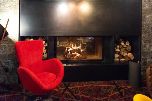 a red chair sitting in front of a fireplace at Chalet Hôtel Le Prieuré & Spa in Chamonix-Mont-Blanc