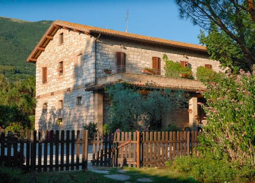 a stone house with a wooden fence in front of it at Agriturismo Il Giardino Dei Ciliegi in Passaggio Di Assisi