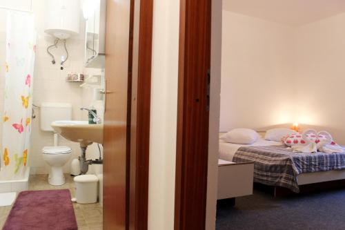 a small bedroom with a bed and a bathroom at Apartments Marinović 3462 in Supetar