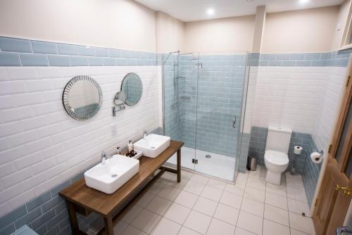 ein Badezimmer mit zwei Waschbecken, einer Dusche und einem WC in der Unterkunft The Highlands Hotel in Glenties