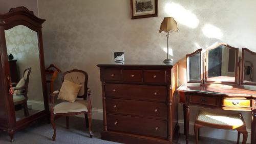 a bedroom with a dresser and a mirror at St David's Guesthouse in Haverfordwest