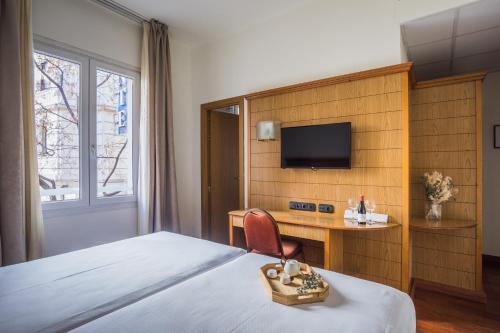 マドリードにあるNegresco Gran Viaのベッド、デスク、テレビが備わるホテルルームです。