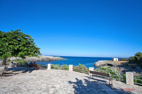 a person sitting on a bench looking at the ocean at Agriturismo Masseria Terra D'Otranto in Otranto